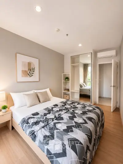Modern bedroom with stylish decor and ample natural light, featuring a cozy bed and mirrored wardrobe.