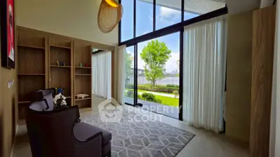 Spacious living room with high ceilings and large windows overlooking a lush garden view.