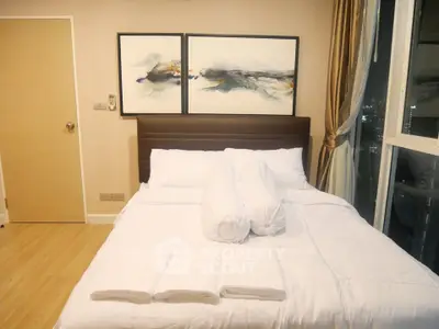 Cozy bedroom with modern decor and city view, featuring a comfortable bed and elegant artwork.