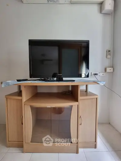 Cozy living room setup with wooden TV stand and modern flat-screen television.