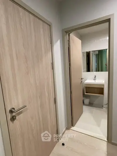 Modern bathroom entrance with sleek wooden doors and stylish sink area.