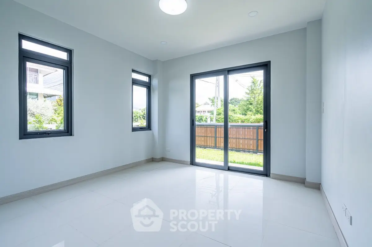 Bright empty room with large windows and garden view, perfect for customization.