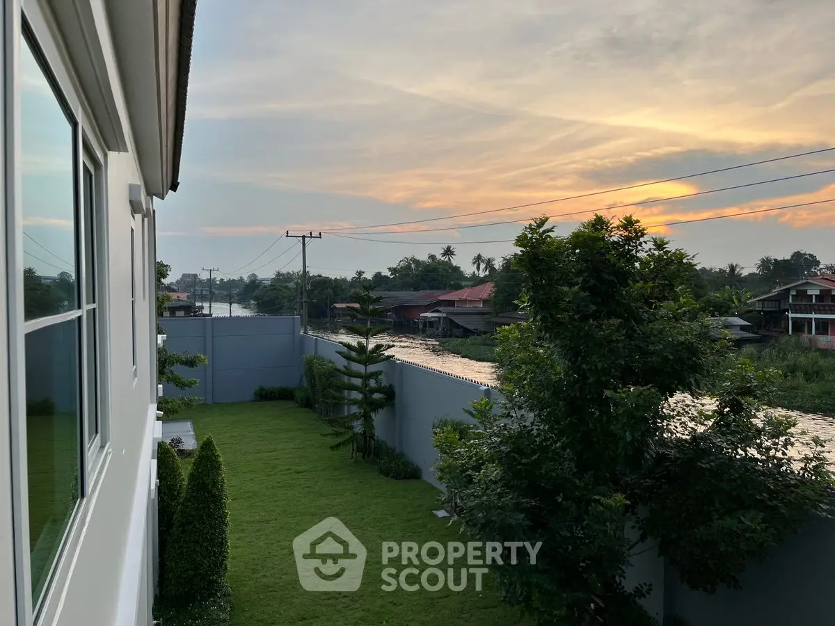 Scenic view from modern home overlooking lush garden and serene neighborhood at sunset.