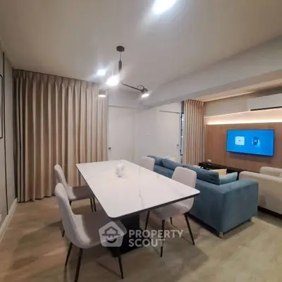 Modern living room with stylish dining area and cozy seating, featuring elegant lighting and contemporary decor.