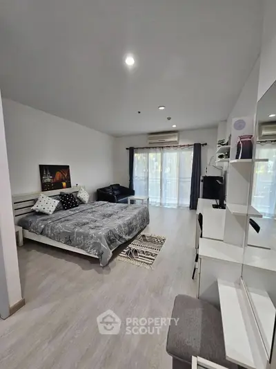 Spacious modern bedroom with stylish decor and large windows for natural light.