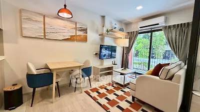 Charming living room with modern decor, cozy seating, and natural light from large window.