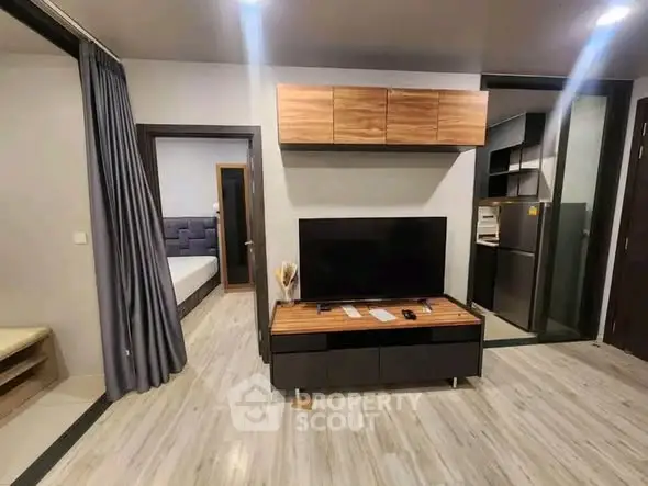Modern living room with sleek TV stand and view into stylish bedroom and kitchen.