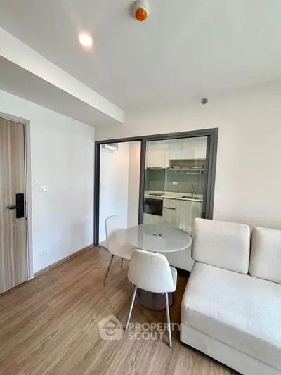 Modern living room with open kitchen and cozy seating area in a stylish apartment.