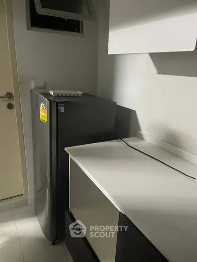 Compact kitchen with modern fridge and sleek cabinetry, ideal for efficient space utilization.