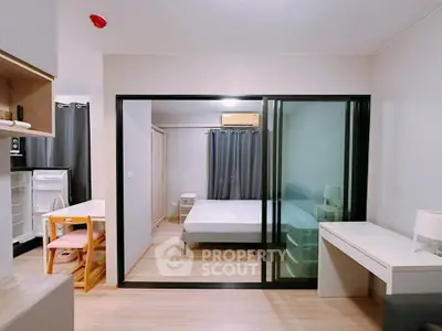 Modern studio apartment with sliding glass doors, cozy bedroom, and compact kitchen area.