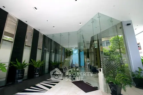 Luxurious modern building entrance with glass walls and lush greenery