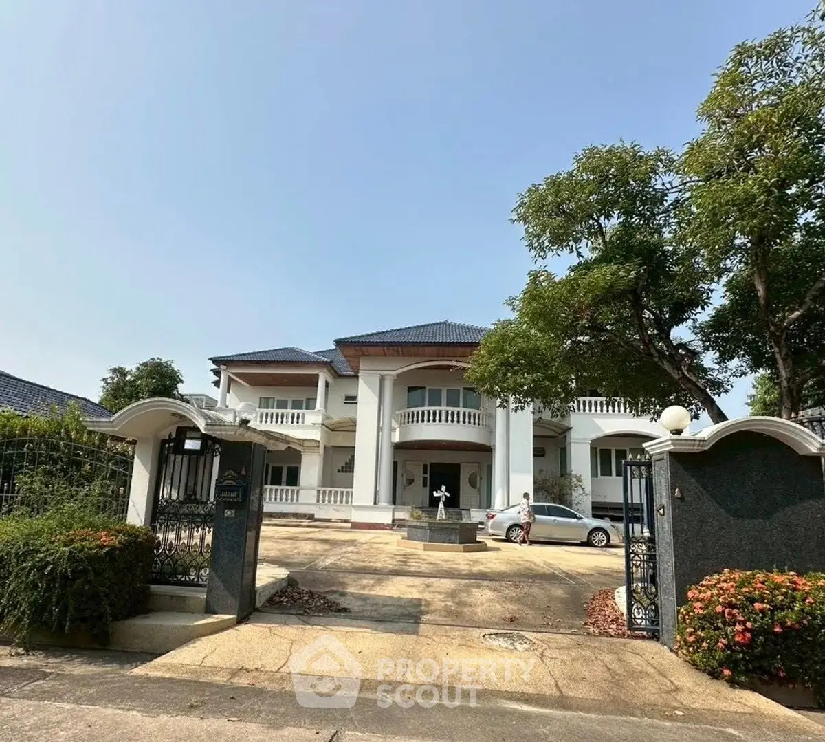 Stunning two-story mansion with grand entrance and lush landscaping, perfect for luxury living.