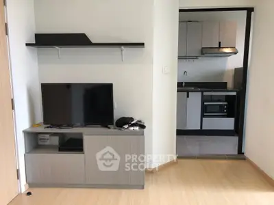 Modern apartment interior with sleek kitchen and cozy living area featuring a flat-screen TV and stylish shelving.