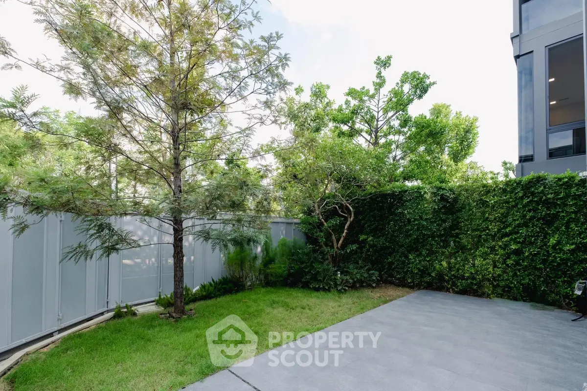 Spacious garden area with lush greenery and modern fencing, perfect for outdoor relaxation.