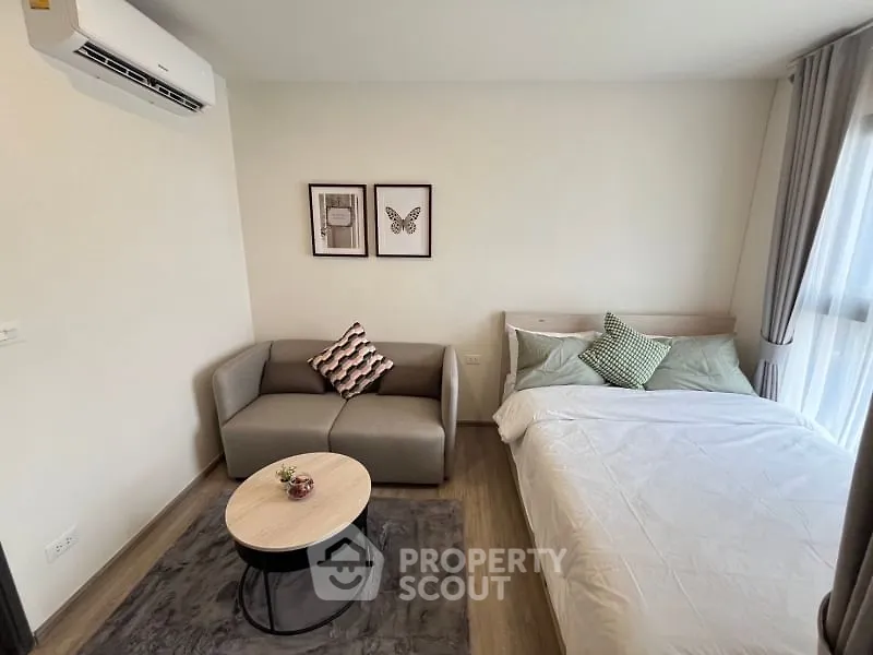 Cozy studio apartment with modern decor, featuring a comfortable bed and stylish sofa in a bright, airy space.