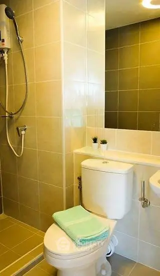 Modern bathroom with sleek tiles and shower, featuring a compact design and stylish fixtures.