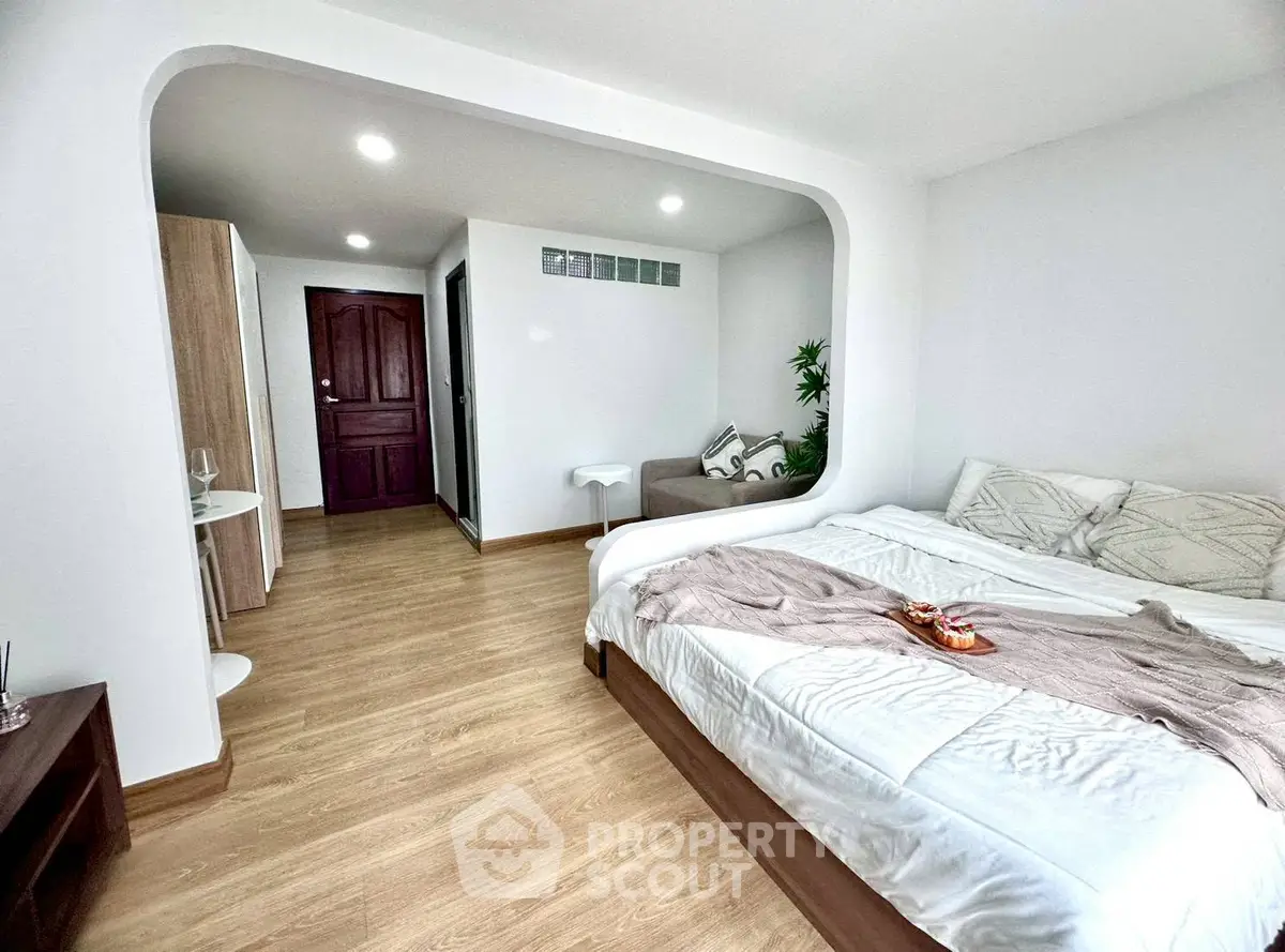Spacious bedroom with modern decor and cozy ambiance, featuring a comfortable bed and stylish wooden flooring.