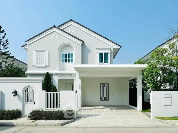 Charming white two-story house with a spacious driveway and lush greenery, perfect for family living.