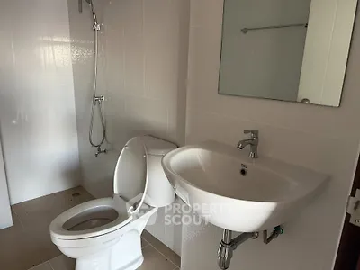 Modern bathroom with sleek fixtures and white tiles, featuring a shower and toilet.