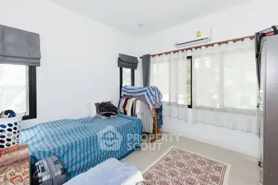 Cozy bedroom with natural light and air conditioning, featuring a single bed and wardrobe.