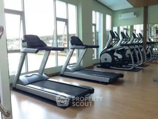 Modern gym with treadmills and exercise bikes in a bright fitness center.
