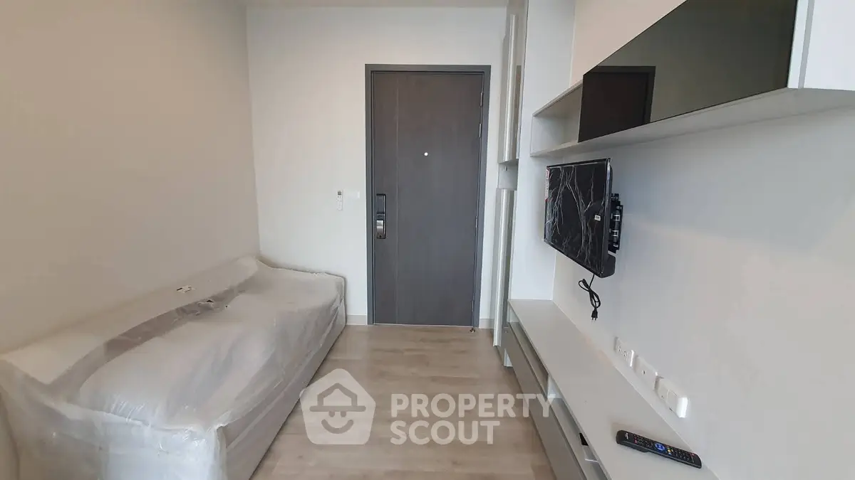 Modern living room with sleek furniture and wall-mounted TV in a compact apartment.