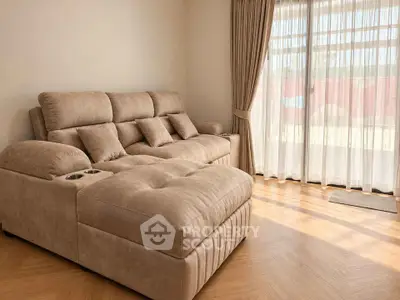 Spacious living room with plush beige sofa and large window for natural light.