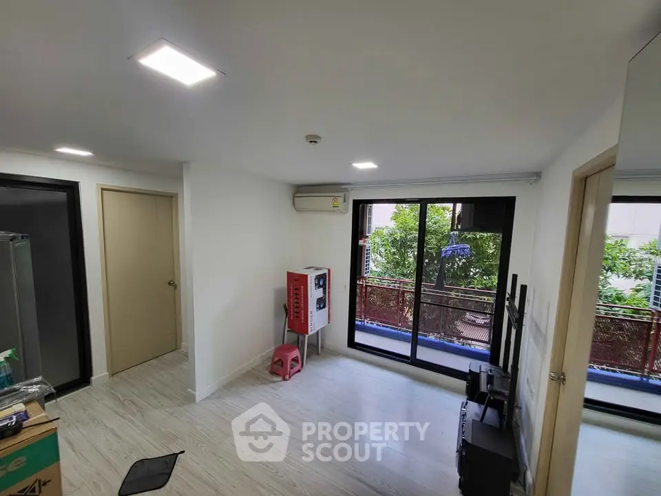 Bright living room with balcony view, modern lighting, and air conditioning in a cozy apartment.