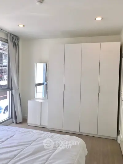 Modern bedroom with white wardrobe and natural light in urban apartment