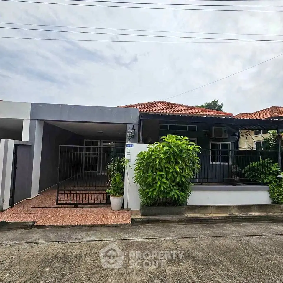 Charming single-story home with red-tiled roof and lush greenery in a serene neighborhood.
