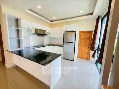 Modern kitchen with sleek white cabinets, black countertop, and large windows for natural light.