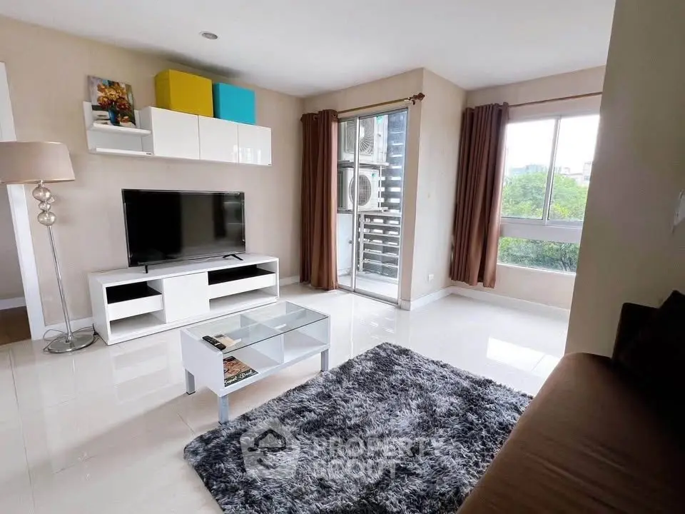 Modern living room with sleek furniture and large windows offering natural light and greenery views.