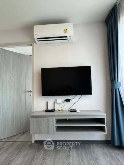 Modern living room with wall-mounted TV and air conditioning unit, featuring sleek furniture and elegant curtains.