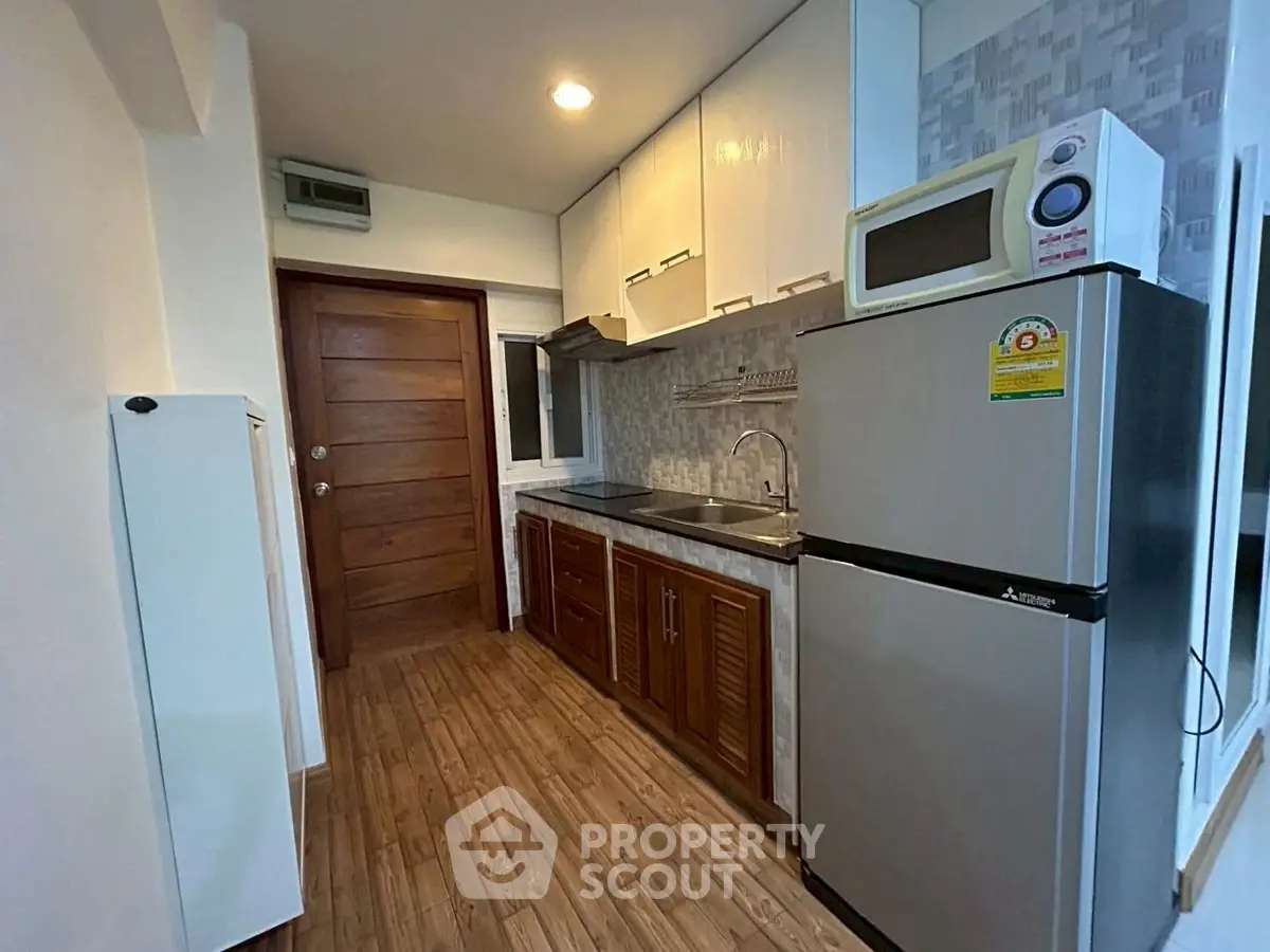 Modern kitchen with wooden cabinets and stainless steel appliances in a cozy apartment.