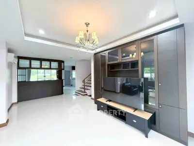 Spacious modern living room with elegant chandelier and built-in entertainment center.