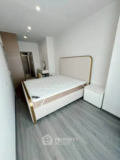 Modern bedroom with sleek flooring and stylish bed frame in a contemporary apartment.