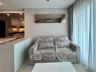 Modern living room with plastic-covered sofa and open kitchen layout