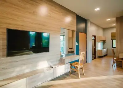 Spacious modern living room with wooden accents and large TV, perfect for relaxation and entertainment.