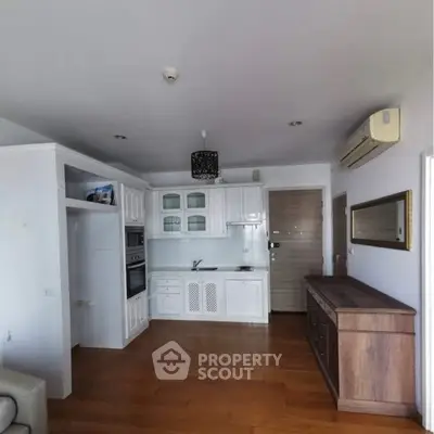 Charming kitchen with white cabinetry and wooden flooring in a cozy apartment setting.