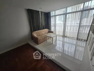 Spacious living room with large windows and city view, featuring a cozy sofa and elegant flooring.