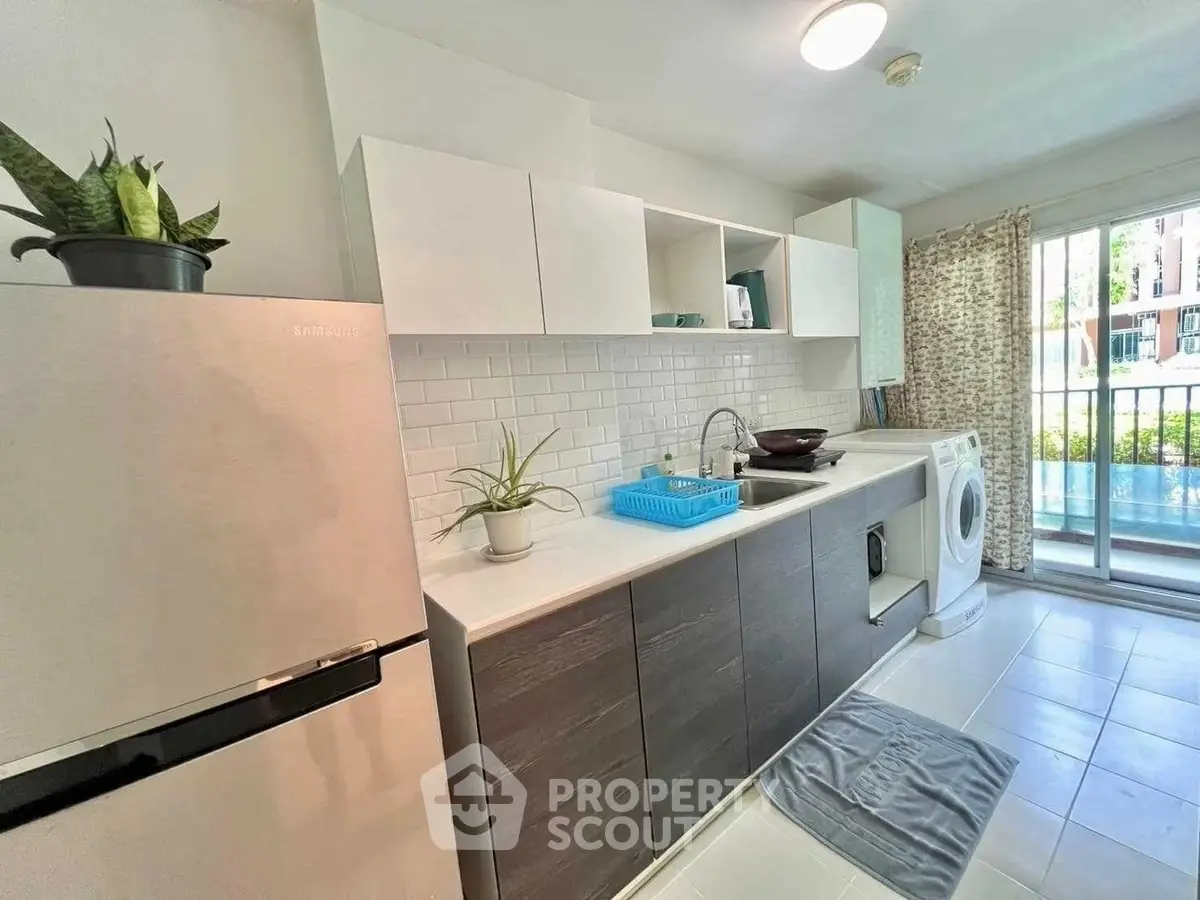 Modern kitchen with sleek cabinets, washing machine, and large window for natural light.