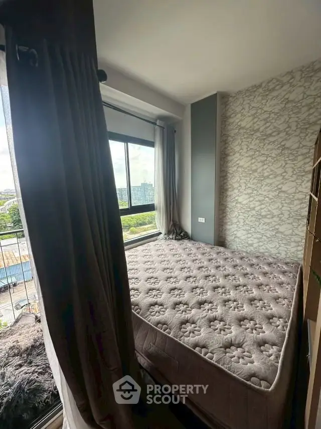 Cozy bedroom with large window offering city view and elegant decor.
