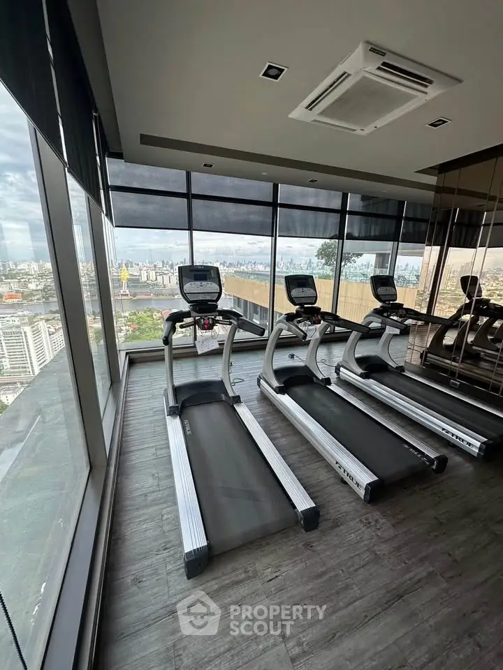Modern gym with treadmills and panoramic city view in luxury high-rise building.
