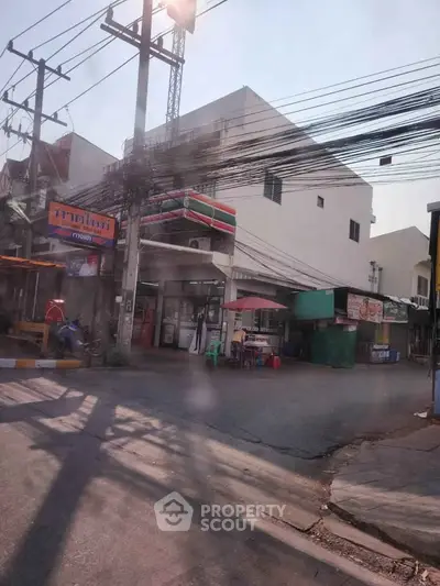 Street view of a commercial building with shops and power lines in an urban area.