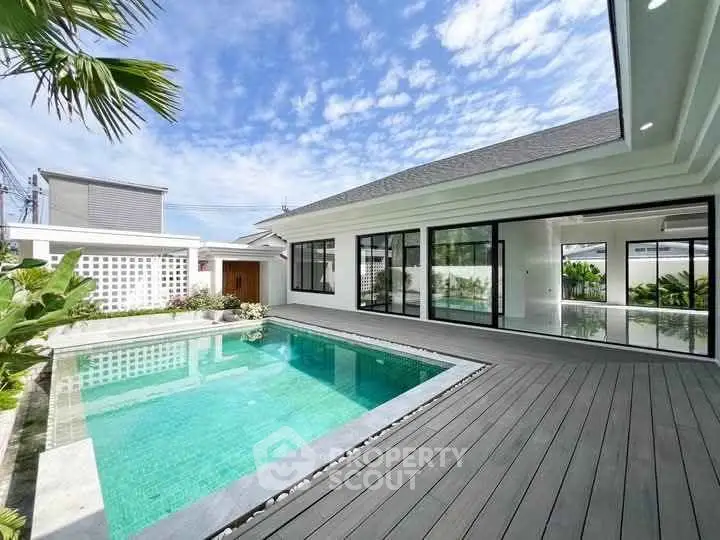 Luxurious modern home with private pool and spacious deck under clear blue sky.