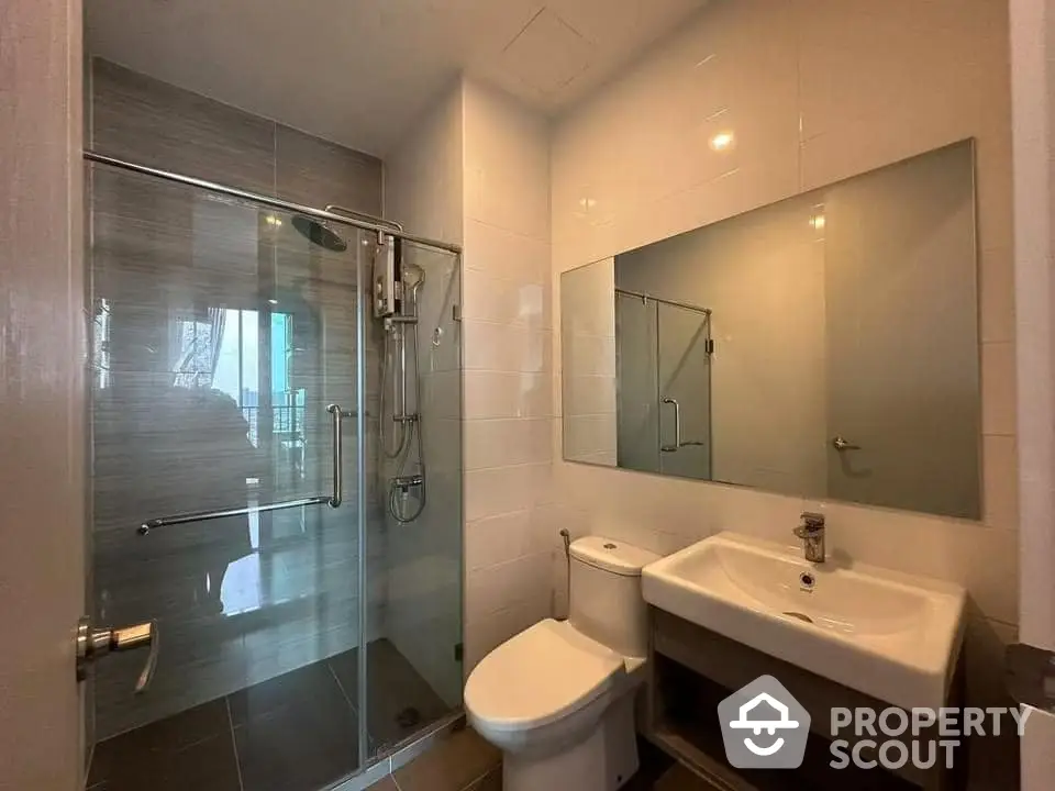 Modern bathroom with glass shower and sleek fixtures in contemporary apartment.