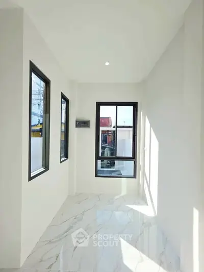 Bright sunlit room with large windows and marble flooring, perfect for modern living.