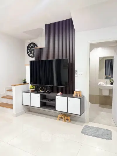 Modern living room with sleek TV setup and stylish staircase