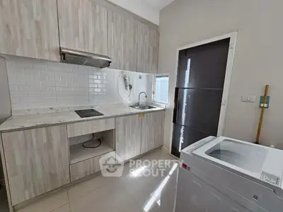Modern kitchen with sleek cabinetry and washing machine, perfect for urban living.