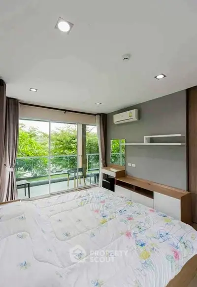 Spacious bedroom with balcony and lush green view, featuring modern furnishings and air conditioning.